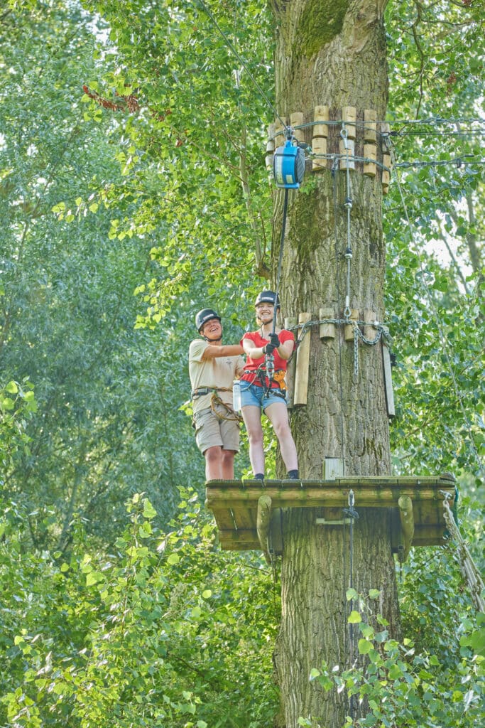 Een mannelijke en vrouwelijke klimmer staan op het platform voor de True Blue en lachen terwijl ze naar de camera kijken.
