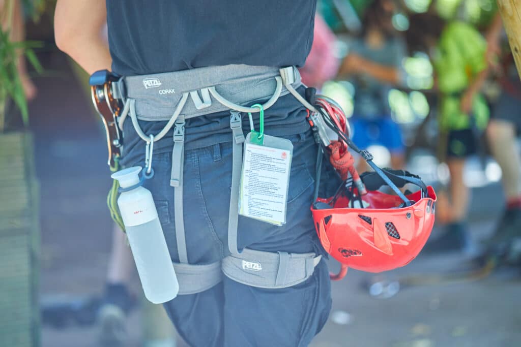 Close-up van de instructeursgordel. Hier is de rode helm te zien, de safetycard met alle veiligheidsregels en een waterfles.