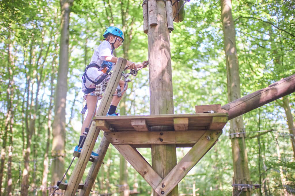Meisje beklimt een ladder om te starten aan een nieuw parcours.