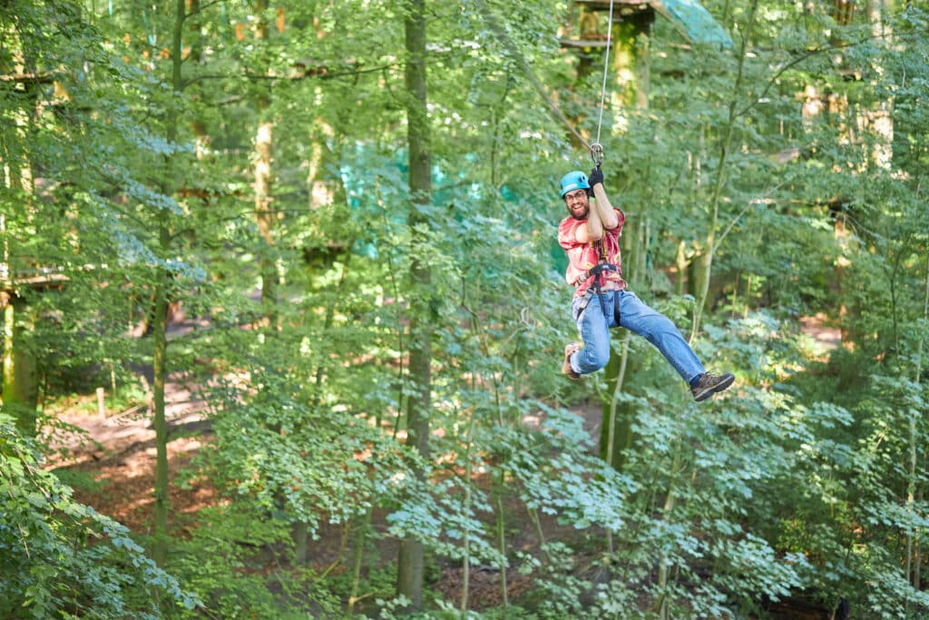 Der Mann schlägt enthusiastisch auf die andere Seite. Er hat sein Bein ausgestreckt und hält seinen Flaschenzug mit beiden Händen fest.