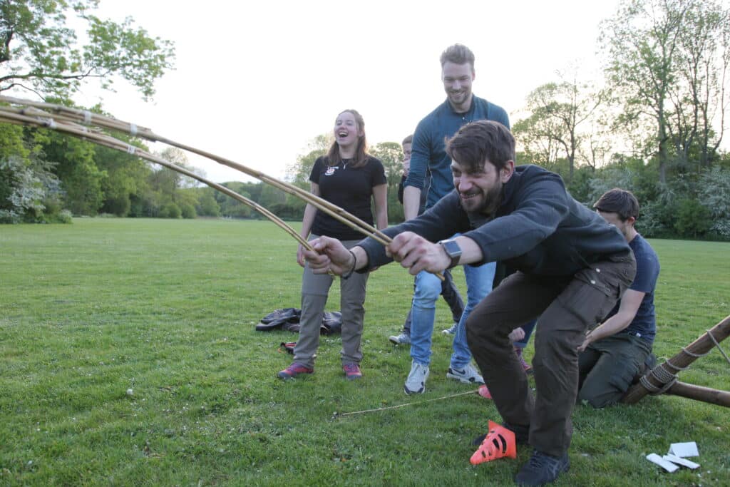 Several people play an Expedition game with strings and sticks