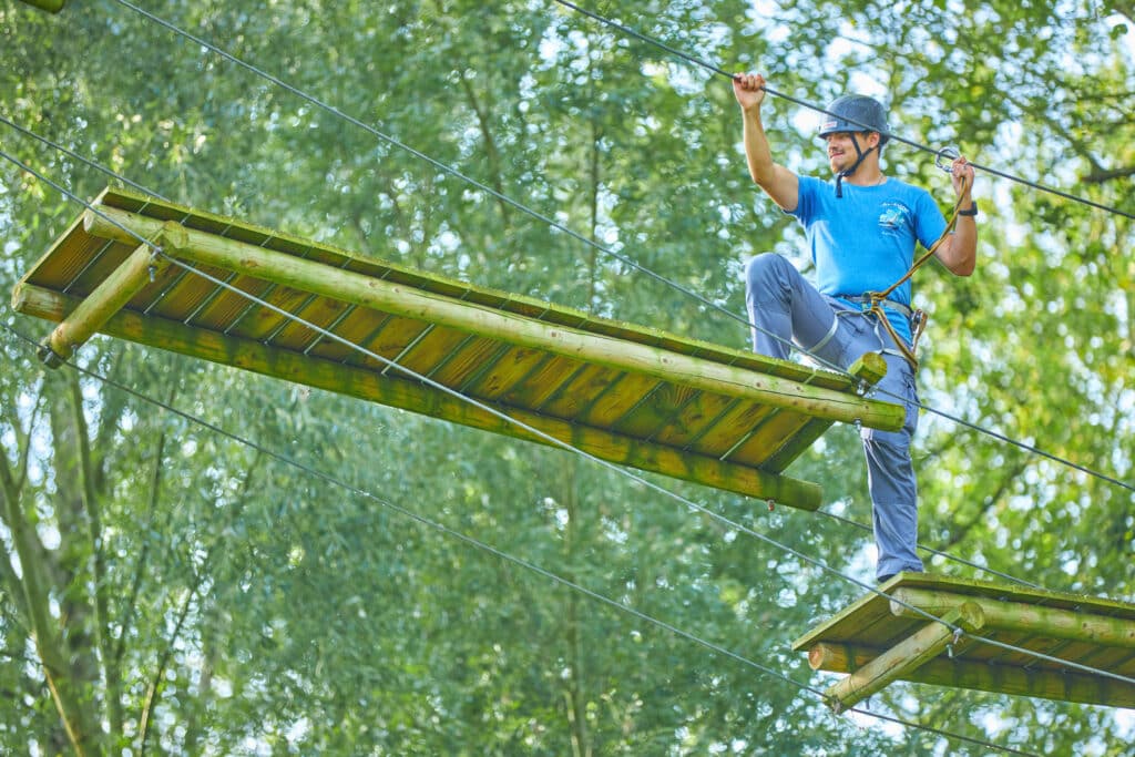 Man met een blauw shirt zet zijn rechtervoet op de volgende houten plank