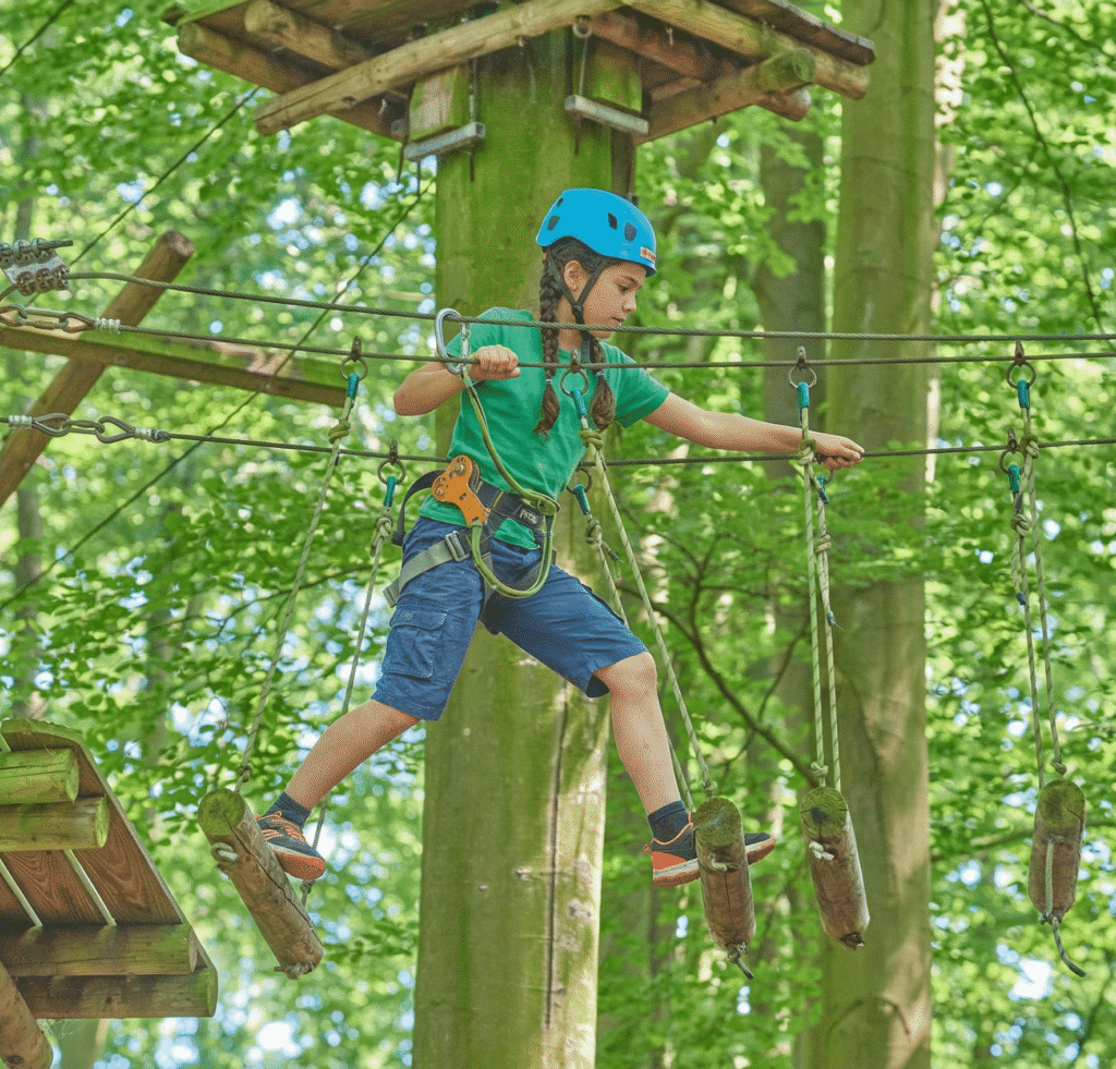 Meisje met twee vlechten, blauwe helm en groen shirt loopt over een brug gemaakt van ronde houten balken, de balken bewegen.