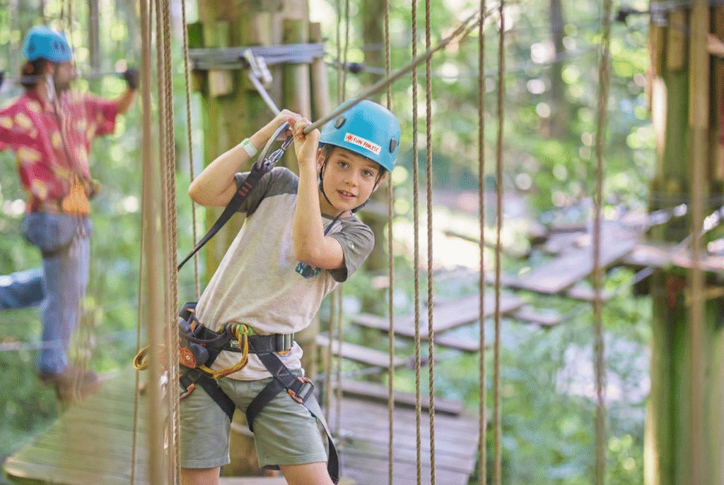 Ein Junge mit einem blauen Helm hält sich an einem Eisenseil fest, während er auf die andere Seite klettert.